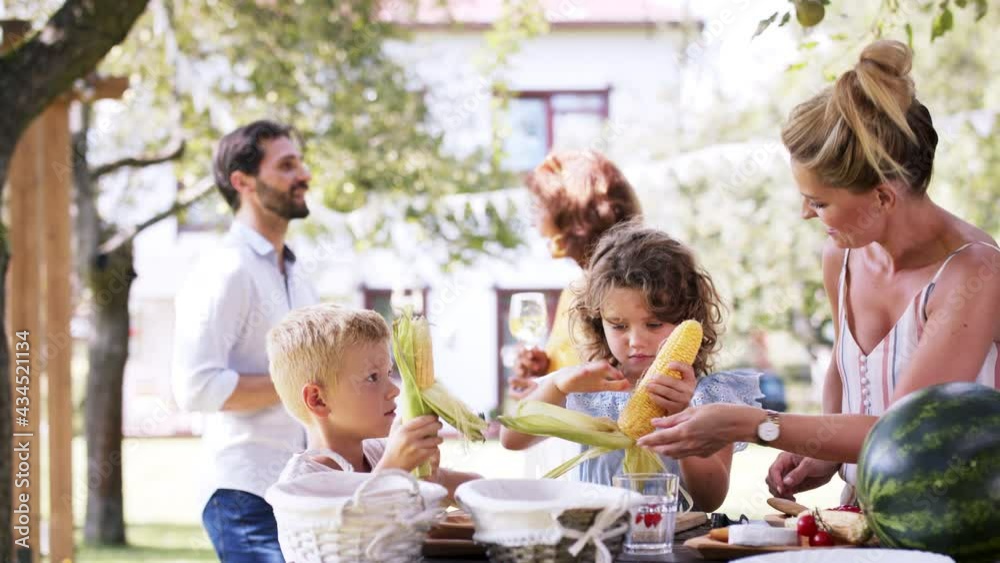 Family having a garden party, kids peeling corn. Family having a garden party, kids peeling corn.