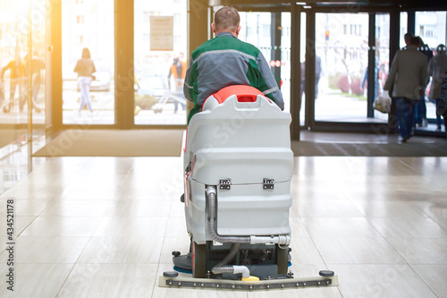 Floor washing machine for sanitation in supermarket. Worker clean floor. Cleaning services worker with washing machine in supermarket shop clean and disinfect floor. Supermarket cleaning services.