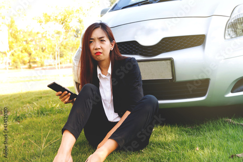 Businesswoman sitting in front of the car, parked on the grass in a place that was unfamiliar with facial expressions, and the eyes were worried because she was lost : Selective Focus photo