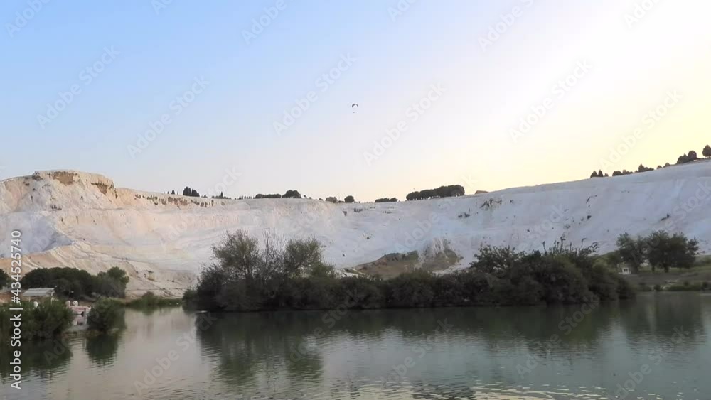Hang gliding paraglider in travertines of Pamukkale, touristic natural world heritage site.Hang glider flying over suspended aeronautics rising morning aloft thermal inflating airship fly aerostat 4K