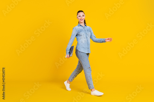 Full length body size woman walking on meeting keeping laptop isolated bright yellow color background