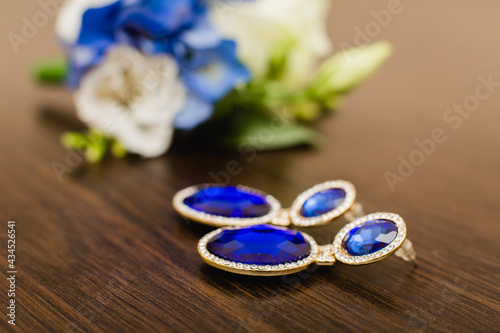 Blue elegant earrings on background of wedding bouquet