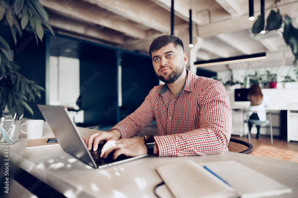 Young man in casual shirt working on computer in office Young man in casual shirt working on computer in office