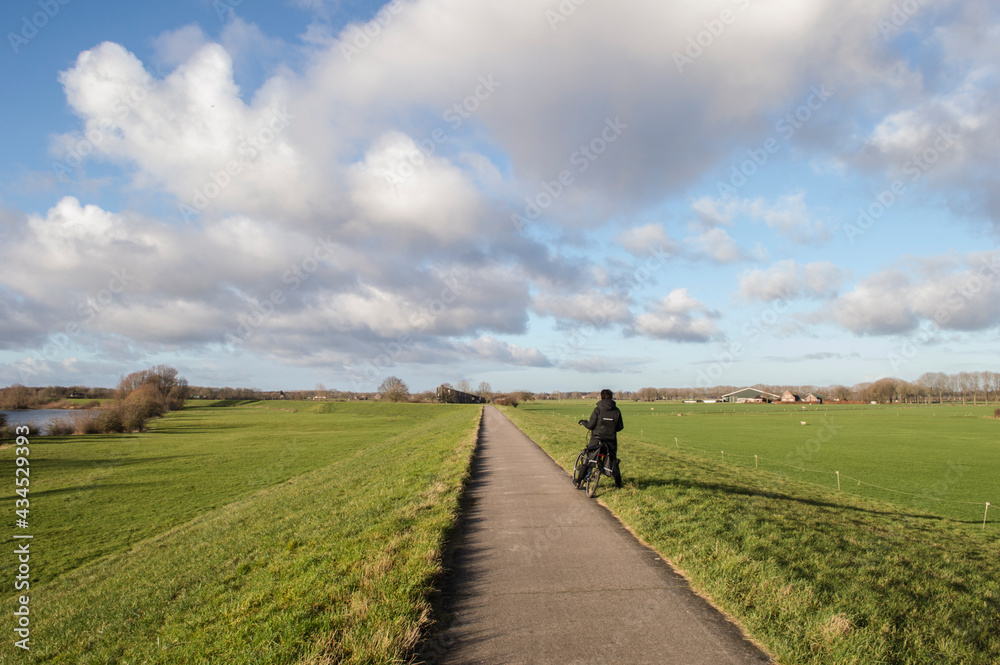 biking road on dike near river IJssel in Dutch polder in winter