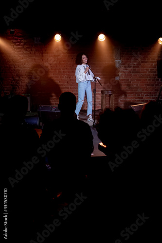 Fotografiet Black African American young female comedian performing her stand-up monologue o