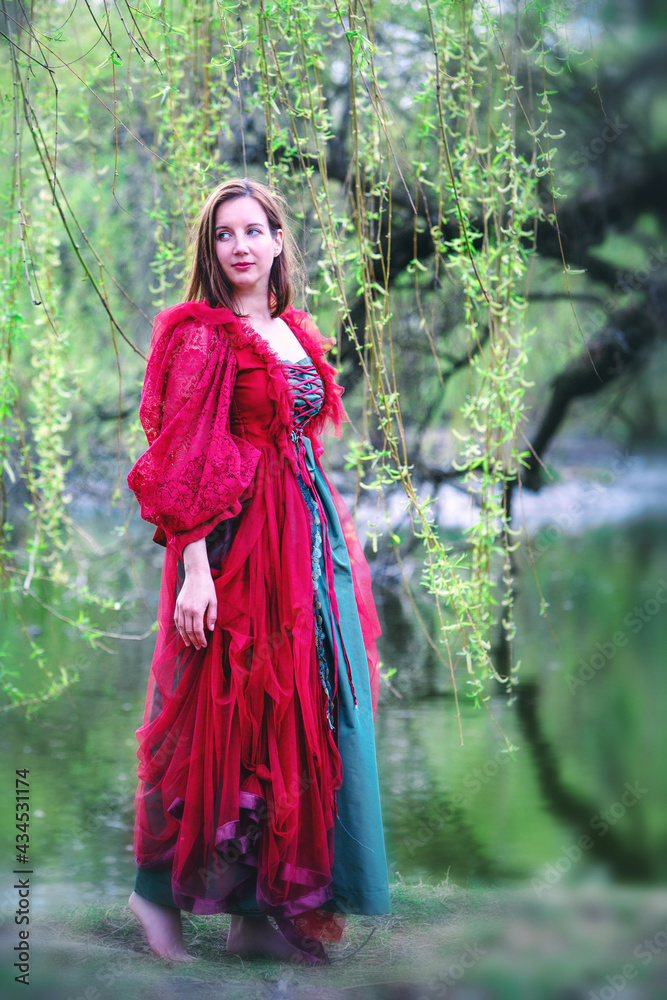 young brunette woman in red gown walking barefoot in nature young brunette woman in red gown walking barefoot in nature