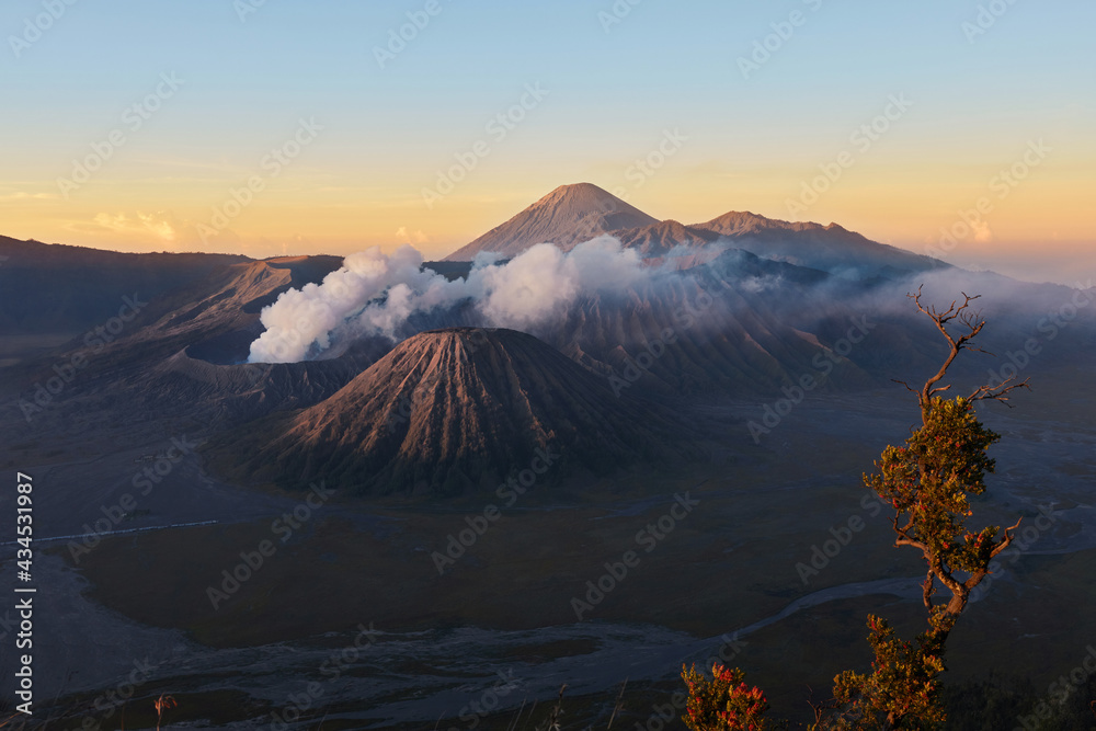 Active volcano in clouds of smoke with crater in depth. Sunrise behind Mount Gunung Bromo volcano in East Java, Indonesia.