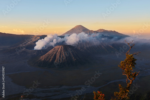 Active volcano in clouds of smoke with crater in depth. Sunrise behind Mount Gunung Bromo volcano in East Java, Indonesia.