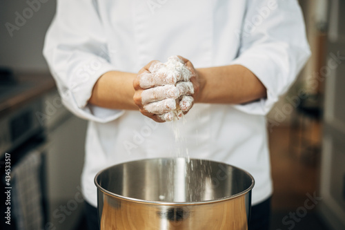 Professional pastry chef in the process of preparing a cake with meringue, in her home kitchen