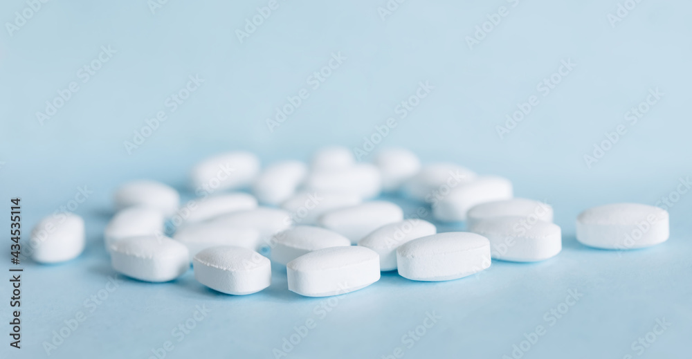 White pills on a light blue background. Healthcare and medicine. White pills on a light blue background. Healthcare and medicine.