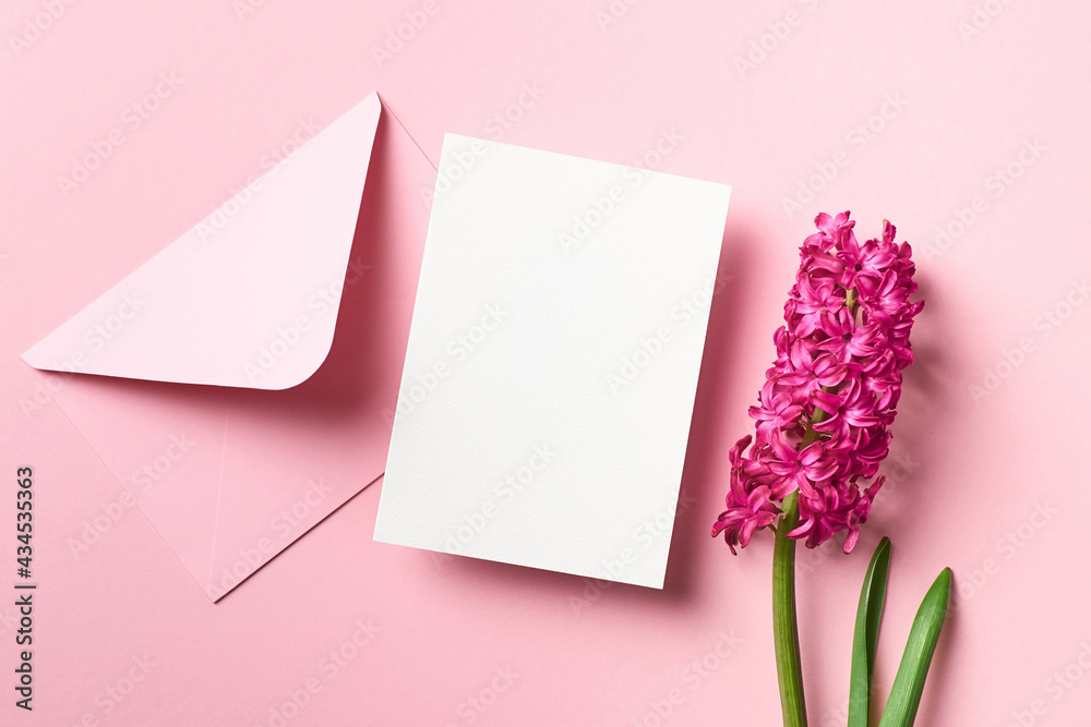 Invitation or greeting card mockup with envelope and spring hyacinth flowers on pink paper background