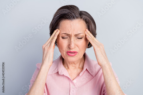 Photo of unhappy upset old woman hold hands head temples headache bad moos isolated on grey color background © deagreez