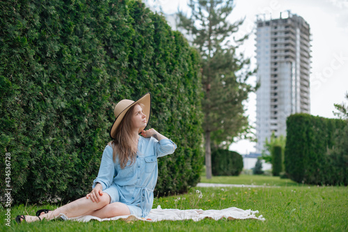 The girl dreams of a new apartment. Romantic girl with hat on picnic in park