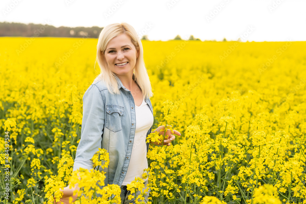 Portrait of attractive woman on blooming rapeseed field with sunset light. Yellow flowers and happy woman Portrait of attractive woman on blooming rapeseed field with sunset light. Yellow flowers and happy woman