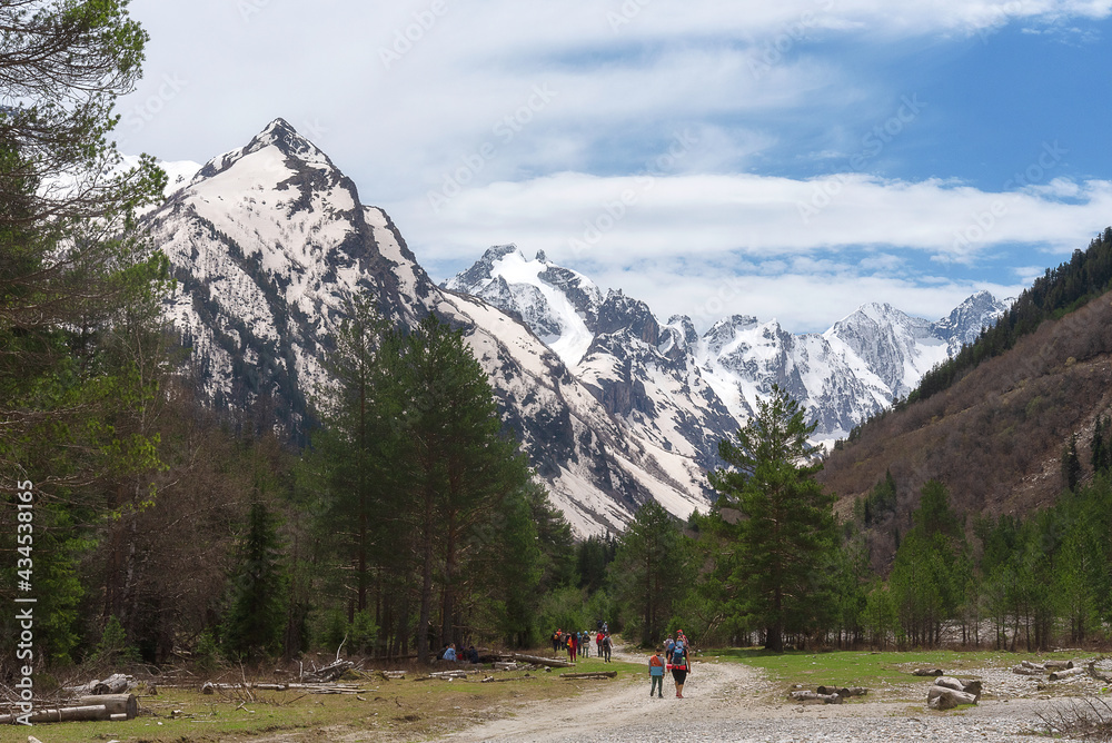 tourists are walking along the road against the background of a large snow-capped mountain