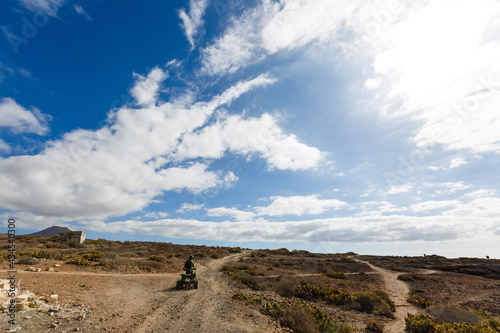 A man riding ATV in sand in protective helmet