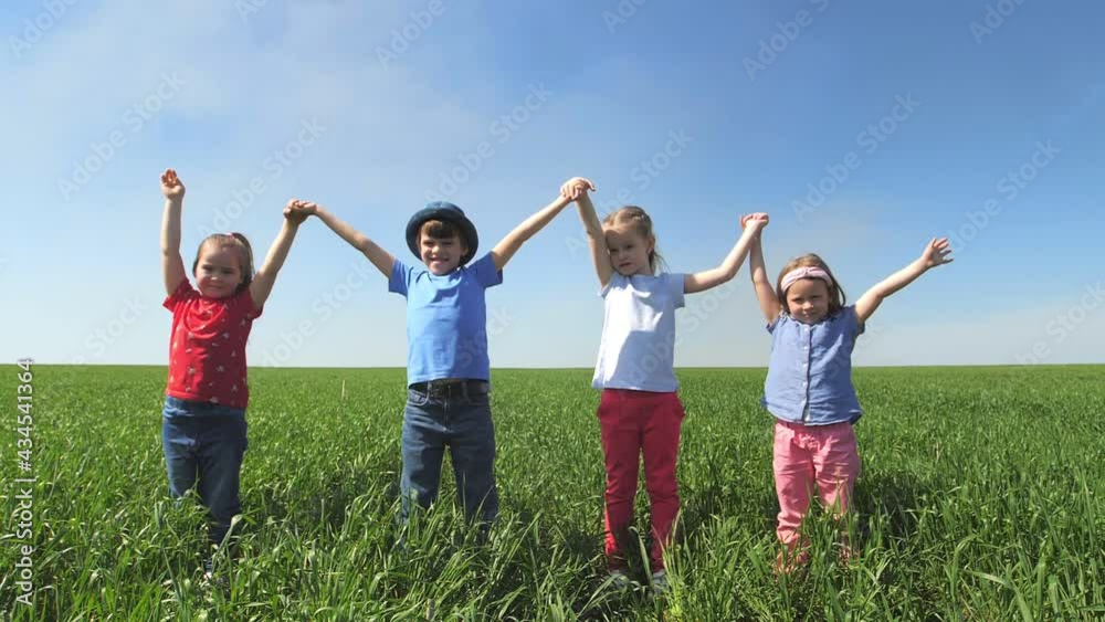 Children stand in a field holding hands, holding them high in the air and laughing. Children stand in a field in the tall grass, laughing and looking at the camera. Slow-motion Children stand in a field holding hands, holding them high in the air and laughing. Children stand in a field in the tall grass, laughing and looking at the camera. Slow-motion