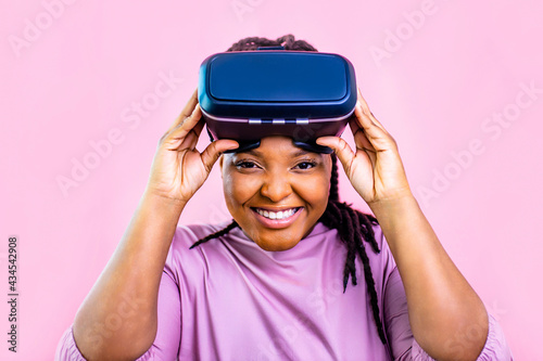 black ethnic woman watching video life simulation in studio pink background