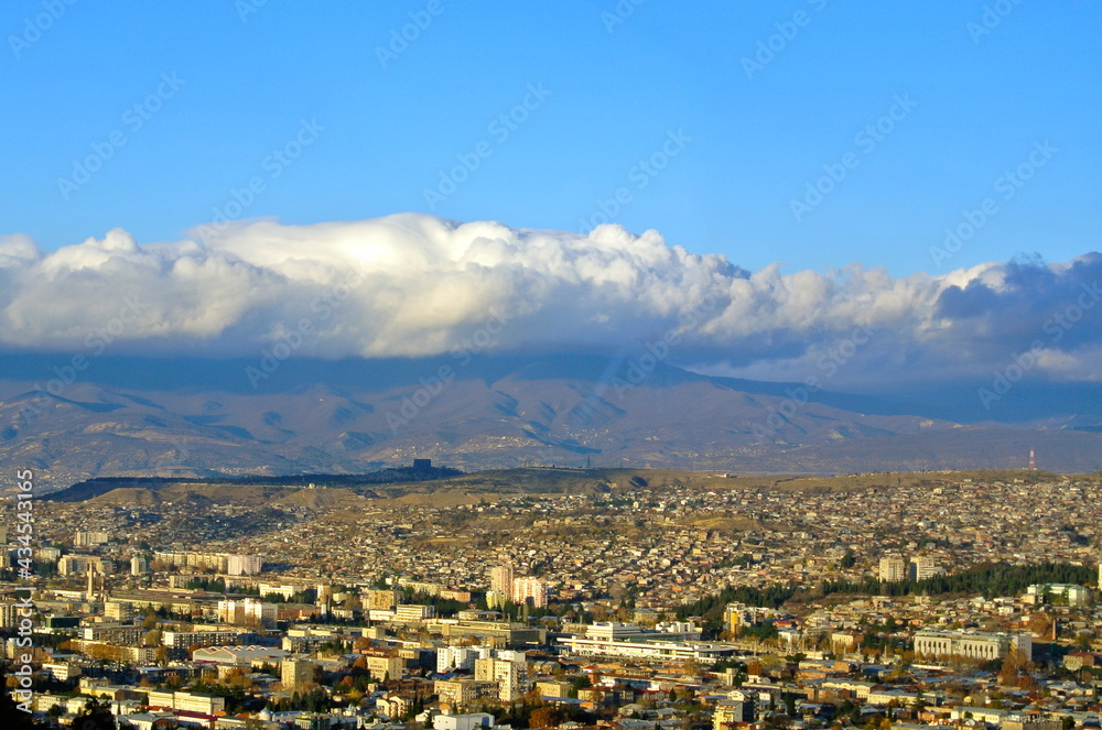 The sky over Tbilisi, the capital of Georgia. Heavy beautiful volumetric clouds cover the mountain background