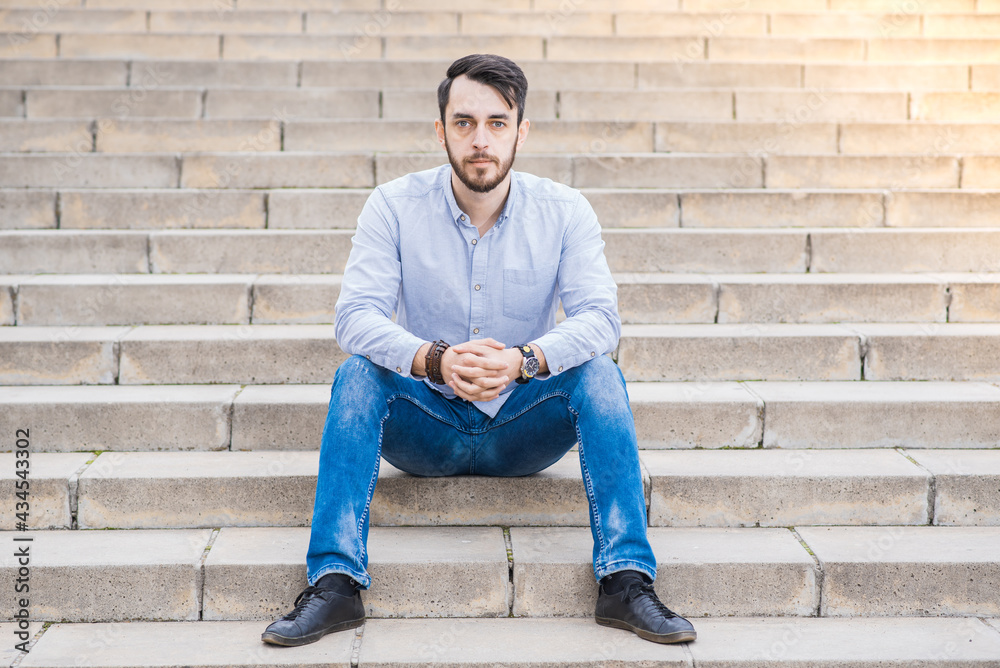 Portrait of a man businessman with a beard who sits on the steps