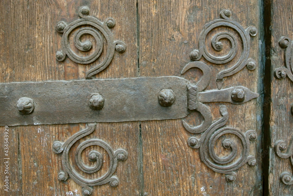 Large grungy wooden gate with metal forged design elements. Weathered wood, historical place in Spain, Europe Large grungy wooden gate with metal forged design elements. Weathered wood, historical place in Spain, Europe