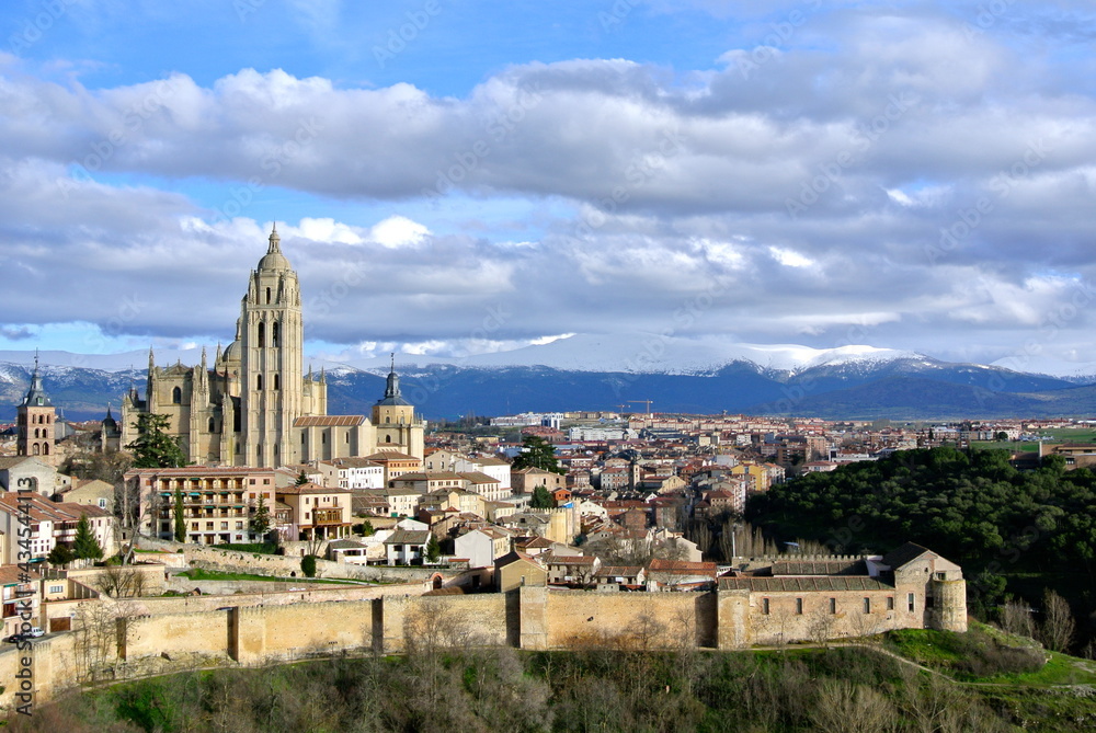 View from the castle to the old city. Backdrop of snow capped mountains and voluminous clouds. Ancient architecture of Segovia, Castile and Leon region, Spain 