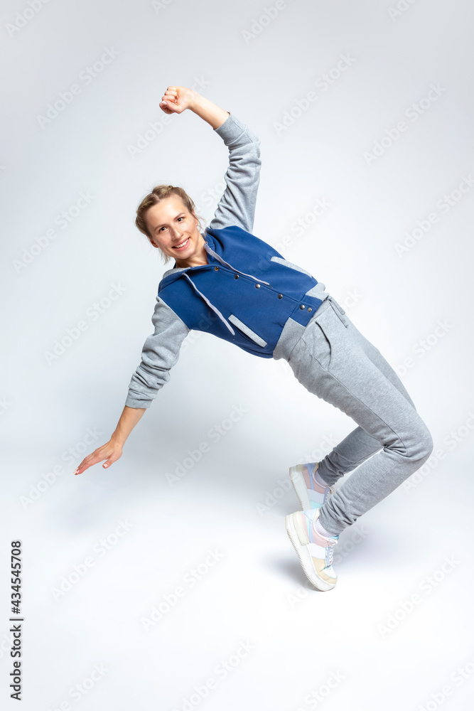 Flexible Female In Streetwear During Body Flex and Stretching Exercises in dance Posing On White Background.