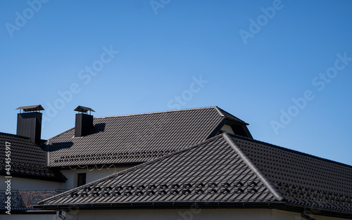 Brown corrugated metal profile roof installed on a modern house. The roof of corrugated sheet. Roofing of metal profile wavy shape. Modern roof made of metal. Metal roofing.