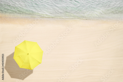 Yellow umbrella on tropical sand beach. Top and aerial view. Ocean coastline. Drone photo. Background