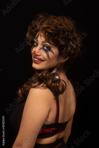 Woman with brown hair and painted face. Joker makeup. Looking at camera. Closeup of face
