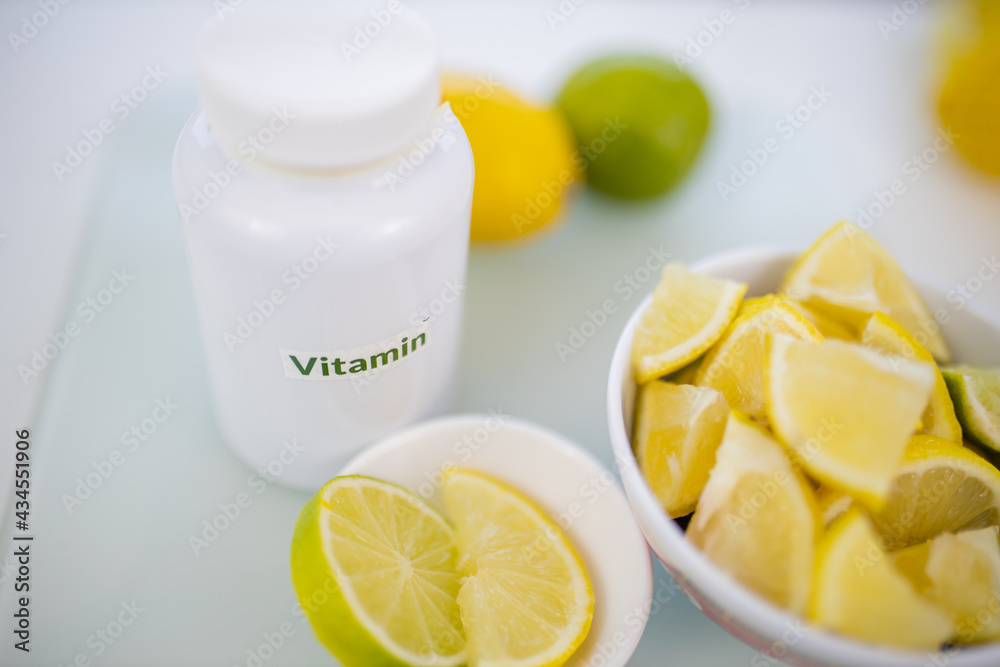 Bottle of vitamins next to bowls of lemon and lime slices Bottle of vitamins next to bowls of lemon and lime slices