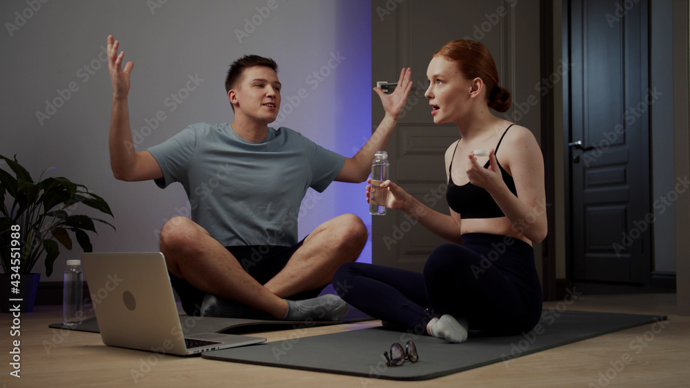 Woman and Man sit on yoga mat and chat and drink water Woman and Man sit on yoga mat and chat and drink water