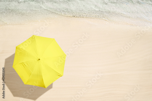 Yellow umbrella on tropical sand beach. Top and aerial view. Ocean coastline. Drone photo. Background