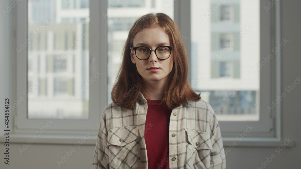 A young girl with glasses stands in an apartment A young girl with glasses stands in an apartment