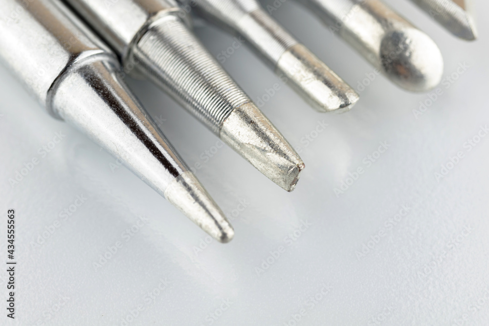Close-up of soldering tips on glass table, silver background with equipment for soldering iron