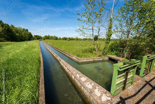 Two small concrete irrigation canals in a rural scene, Padan Plain or Po valley (Pianura Padana, Italian). Mantua province, Italy, southern Europe.