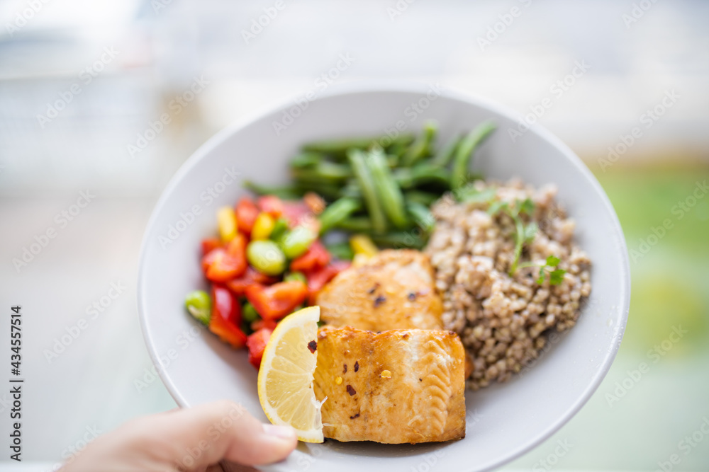 Hand holding salmon and buckwheat dish with green beans Hand holding salmon and buckwheat dish with green beans