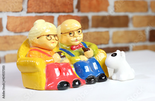 A beautiful vintage grandfather  grandmather and dog ceramic doll. orange brick wall background. photo