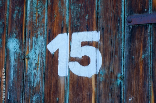 White colour number fifteen on an old abandoned brown colour wooden gate 