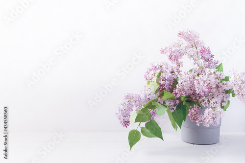 Floral layout with branches of blooming lilacs in a gray pot. Spring, summer template for banner, postcard, social media. Copy space.