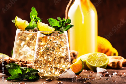 Ginger Ale Alcoholic Cocktail with Beer, Lime, Lemon and Mint Leaves in glaass on wooden table photo