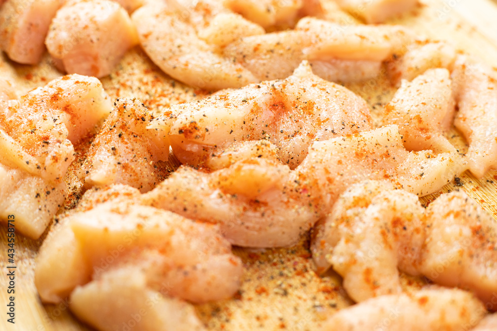 Raw pieces of chicken seasoned with various spices lying on a wooden board