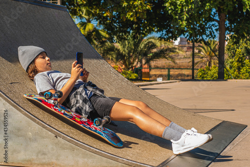 Girl lying on a skate ramp with her mobile phone