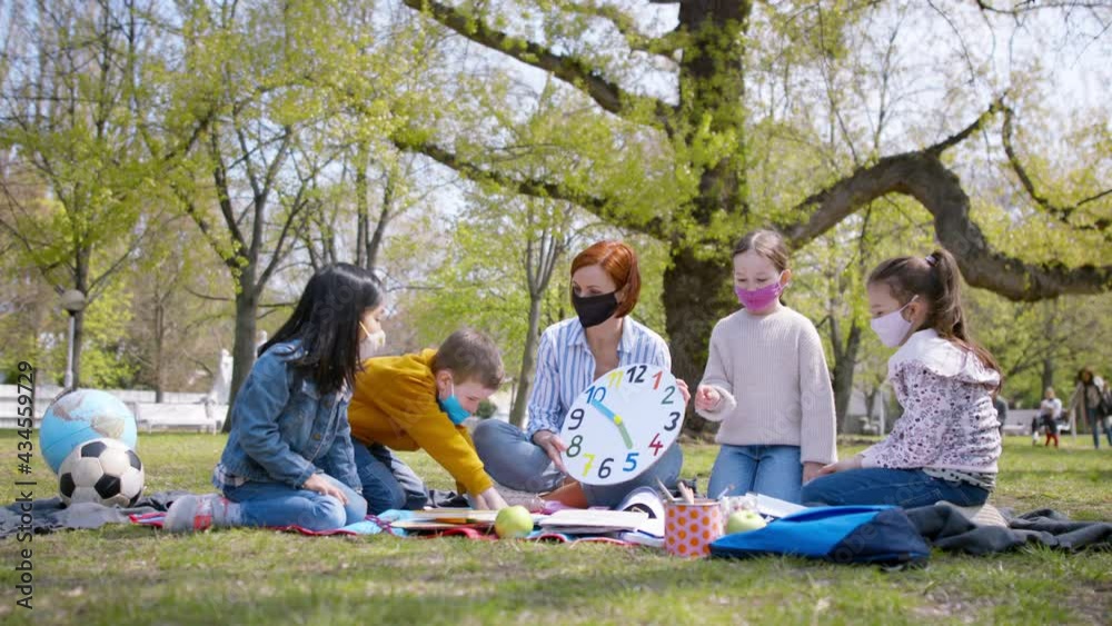 Teacher with small children sitting outdoors in city park, learning group education and coronavirus concept. Teacher with small children sitting outdoors in city park, learning group education and coronavirus concept.