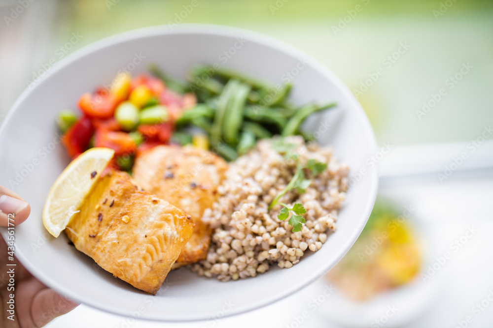 Hand holding salmon and buckwheat dish with green beans Hand holding salmon and buckwheat dish with green beans