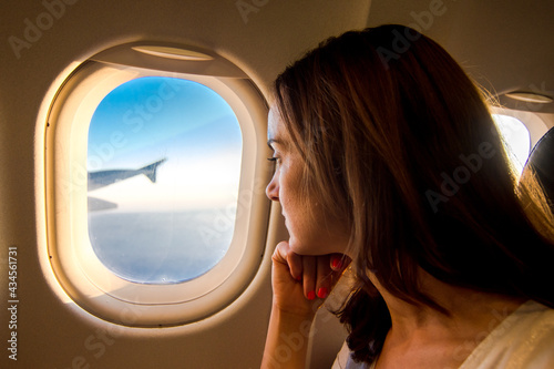 Young woman looking through window in airplane.Girl sitting in airplane near window.