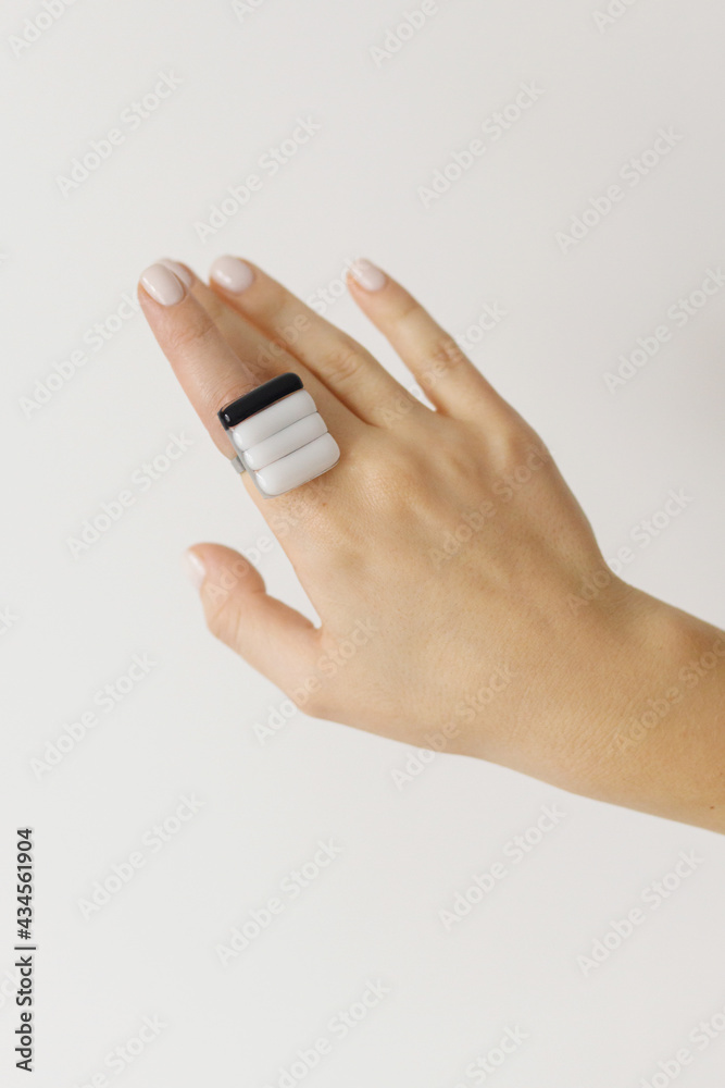 Stylish modern white and black square ring on beautiful hand on white background. Unusual fashionable fused glass ring on female hand with white manicure. Contemporary gift Stylish modern white and black square ring on beautiful hand on white background. Unusual fashionable fused glass ring on female hand with white manicure. Contemporary gift