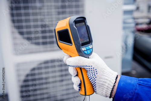 Technician uses a thermal imaging infrared thermometer to check the condensing unit heat exchanger.