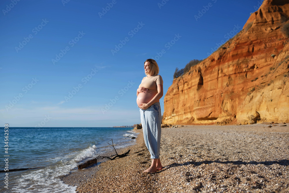 a pregnant woman standing on the seashore