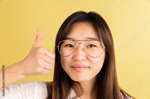 Asian young woman's portrait on yellow studio background. Concept of human emotions, facial expression, youth, sales, ad.